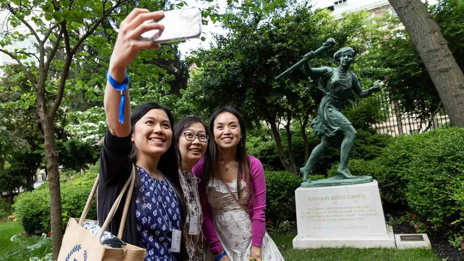 Women pose with runner statue
